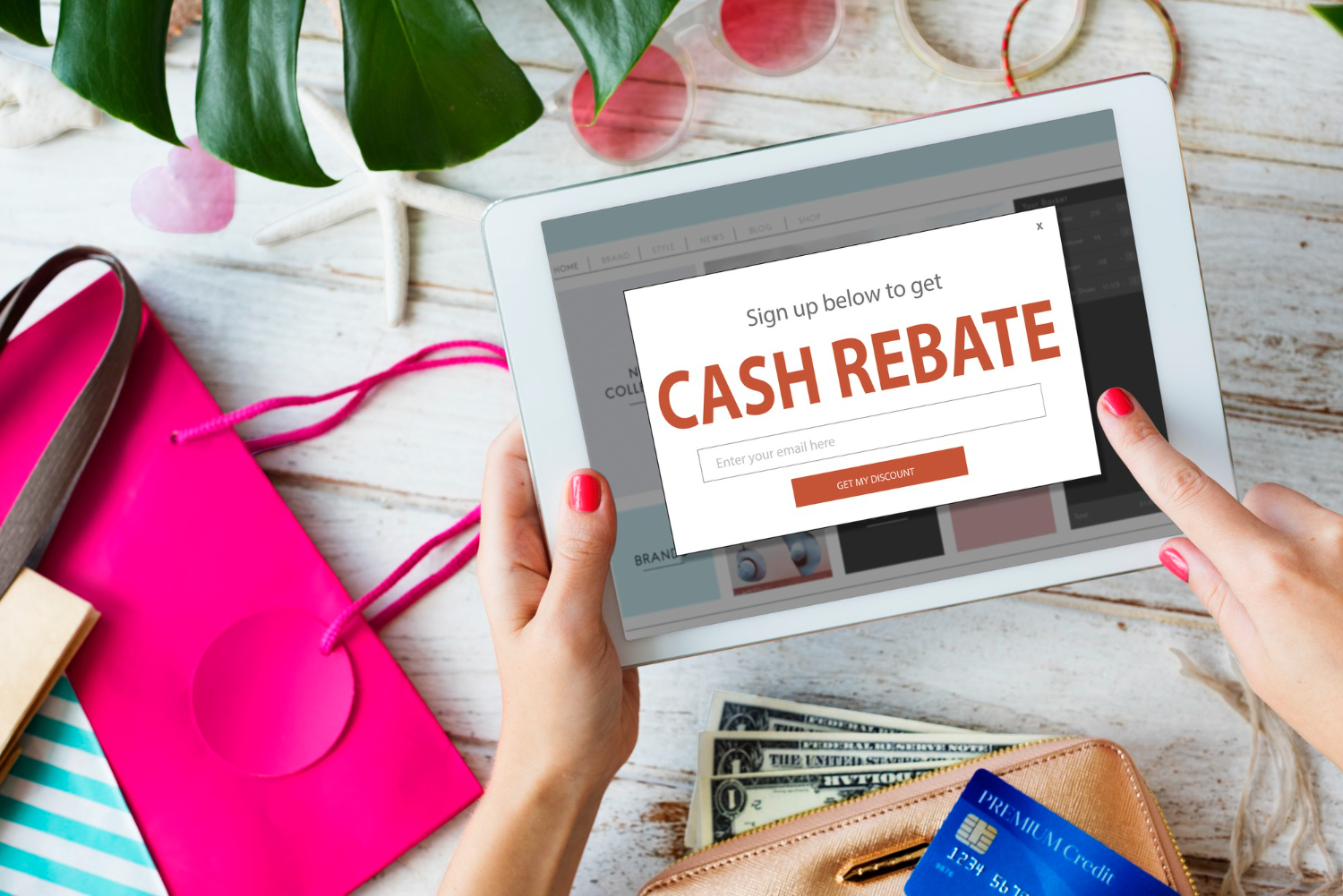 Tablette affichant une offre de cashback entourée d'articles de shopping et d'une carte bancaire.